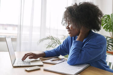 Afro businesswoman working on laptop at home office - AAZF00698