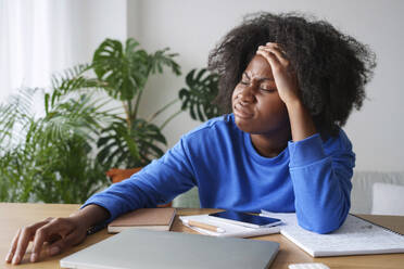 Frustrated Afro businesswoman with head in hand at desk - AAZF00702