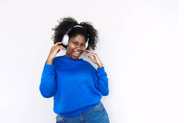 Afro-Frau genießt Musik mit Kopfhörern vor weißem Hintergrund - AAZF00709