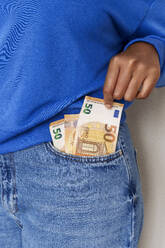 Woman taking paper currency from jeans pocket - AAZF00717