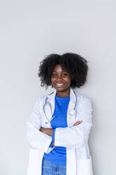 Junger Afro-Arzt mit verschränkten Armen vor weißem Hintergrund - AAZF00718