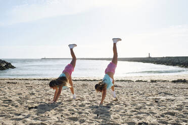 Zwillingsschwestern machen Handstand am Strand - ASGF03661