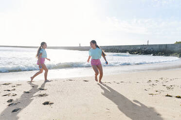 Zwillingsschwestern spielen mit Spritzpistolen am Strand - ASGF03687