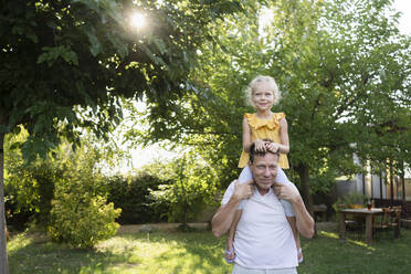 Father carrying daughter on shoulders in backyard - SVKF01414