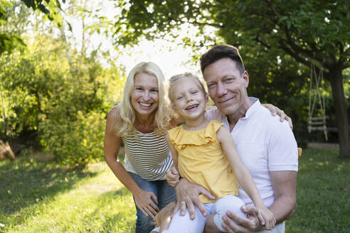 Glückliche Eltern verbringen ihre Freizeit mit ihrer Tochter im Garten - SVKF01416