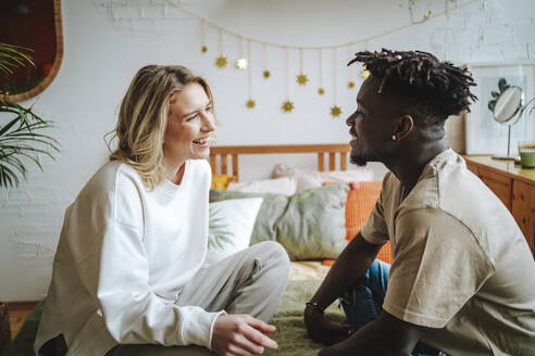 Happy couple sitting and discussing on bed at home - MDOF01308