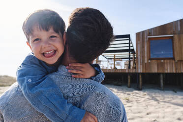 Glücklicher Junge mit Vater am Strand an einem sonnigen Tag - ASGF03710