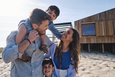 Happy family enjoying together in front of beach house - ASGF03718