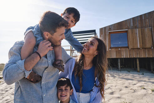 Glückliche Familie genießt zusammen vor dem Strandhaus - ASGF03718