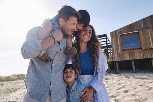 Glückliche Familie, die gemeinsam vor dem Strandhaus Spaß hat - ASGF03719