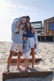 Happy family standing on steps in front of house - ASGF03722