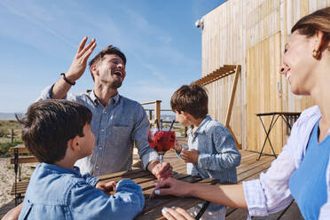 Glückliche Mutter und Vater sitzen mit ihren Kindern am Tisch und genießen die Ferien an einem sonnigen Tag - ASGF03728