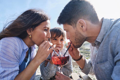 Vater und Mutter trinken Saft mit ihrem Sohn an einem sonnigen Tag - ASGF03737