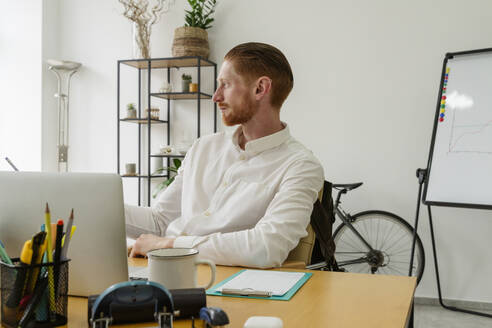 Thoughtful businessman sitting at desk in office - OSF01637