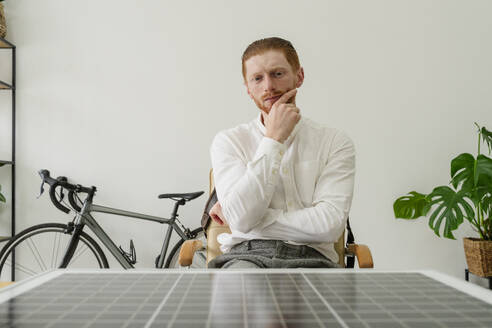 Geschäftsmann prüft Solarpanel am Schreibtisch im Büro - OSF01645