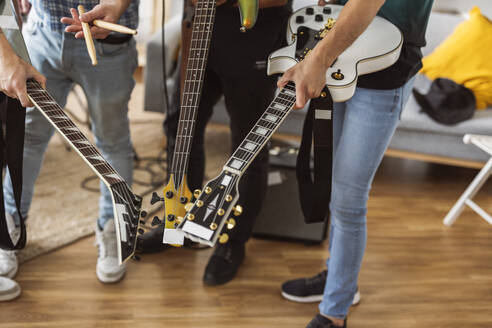 Musiker, die mit Gitarren und Schlagzeugstöcken zu Hause stehen - JCCMF10468