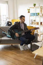 Young musician playing guitar at home - JCCMF10473