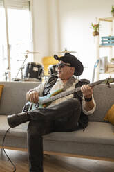 Älterer Gitarrist übt Gitarre auf dem Sofa zu Hause - JCCMF10484