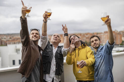 Glückliche Freunde gestikulieren und genießen gemeinsam ein Bier auf dem Dach - JCCMF10488