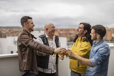 Happy friends toasting beer glasses together on rooftop - JCCMF10489