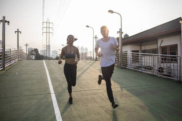 Freunde joggen gemeinsam auf dem Fußweg - IKF00843