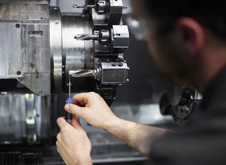 Techniker repariert Bohrer an einer Metallmaschine in einer Fabrik - CVF02413