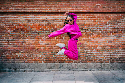 Fröhliche Frau springt vor eine Mauer - GDBF00068