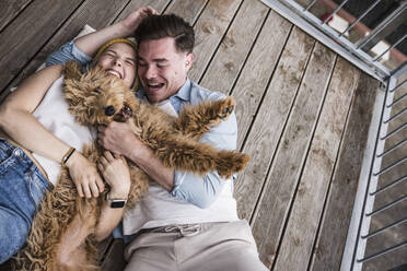 Happy young couple enjoying with dog on balcony - UUF28805