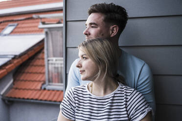 Lächelndes Paar lehnt sich auf dem Balkon an die Wand - UUF28831