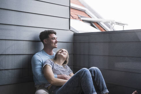 Happy woman with man leaning on wall - UUF28835