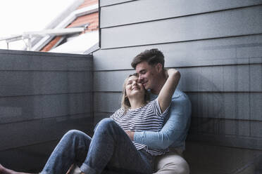 Loving couple leaning on wall on balcony - UUF28837