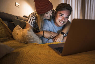 Verliebtes Paar, das zu Hause gemeinsam einen Laptop benutzt - UUF28862