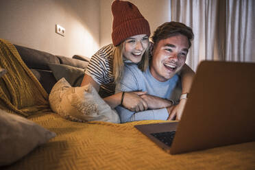 Verliebtes junges Paar benutzt Laptop im Wohnzimmer - UUF28865