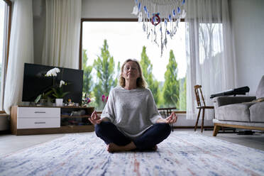 Senior woman practicing meditation at home - ANNF00281