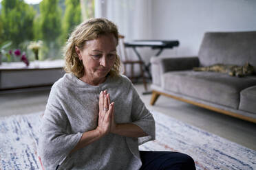 Senior woman with hands clasped practicing yoga at home - ANNF00283