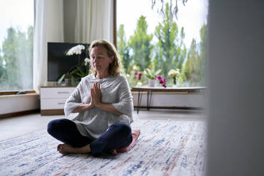 Senior woman with hands clasped practicing meditation at home - ANNF00284