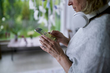 Ältere Frau schreibt Textnachrichten und benutzt ihr Smartphone zu Hause - ANNF00290