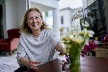 Happy senior woman touching flowers at home - ANNF00293