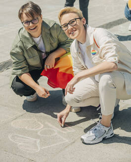 Glückliches lesbisches Paar schreibt mit Kreide auf den Boden - VSNF01059