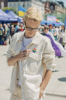 Lächelnde Frau mit Regenbogenabzeichen bei einer Gay-Pride-Veranstaltung - VSNF01060