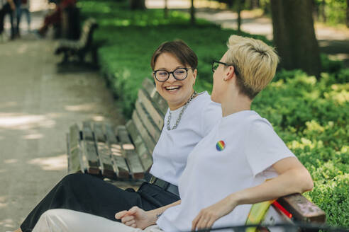 Glückliche Lesben sitzen auf einer Bank im Park - VSNF01066