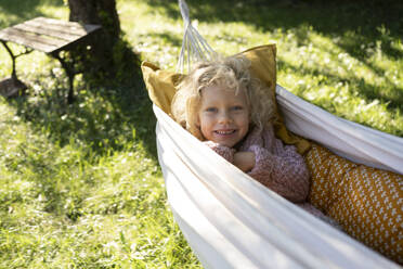 Lächelndes Mädchen auf Hängematte im Garten liegend - SVKF01435