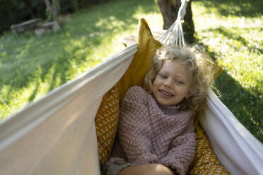 Lächelndes Mädchen liegt in der Hängematte im Garten - SVKF01436