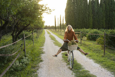 Happy woman riding bicycle on footpath - SVKF01442