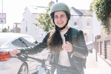 Happy delivery person gesturing with bicycle at footpath - AMWF01388