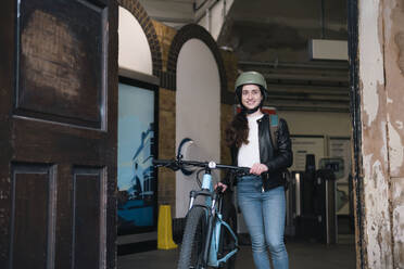 Glücklicher Zusteller mit Fahrrad in der Tür stehend - AMWF01391