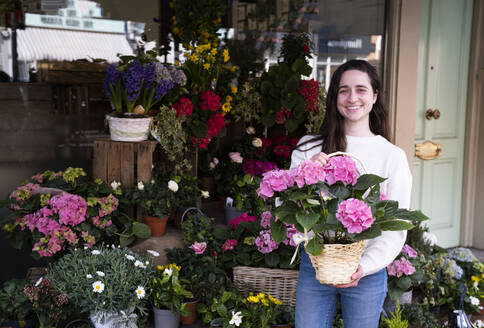 Glückliche Floristin mit einem Blumenstrauß im Laden stehend - AMWF01399