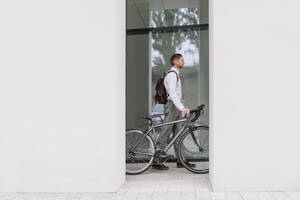 Geschäftsmann mit Fahrrad im Bürokorridor - OSF01657