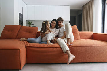 Glückliche Familie, die zusammen auf dem Sofa zu Hause sitzt - SYEF00429