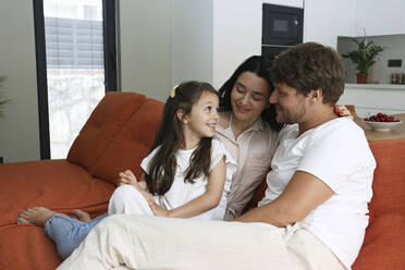 Mutter und Vater verbringen ihre Freizeit mit ihrer Tochter auf dem Sofa zu Hause - SYEF00432